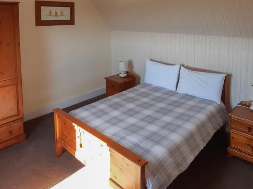 UplawmoorOld Barn Farmhouse的一间卧室配有一张带 ⁇ 子毯子和2个床头柜的床
