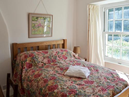 SoutergateWoodburn Cottage的一间卧室配有一张带彩色床罩的床