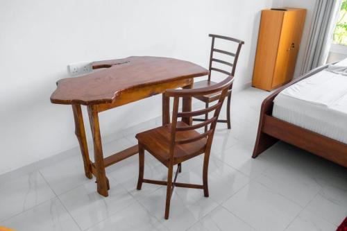 卡图纳耶克G A Villa Airport Transit Hotel的一张木桌和椅子,位于一个配有床的房间