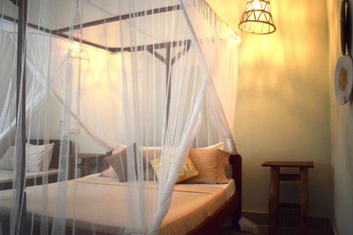 布韦朱Maryam Garden Apartments & Villa的卧室配有带白色窗帘的天蓬床
