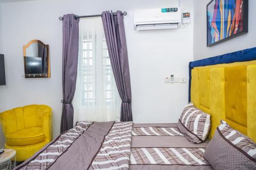 AmuwoSpectacular 3/4-Bed-Apt With 24hrs Power And FAST Wi-Fi的一间卧室配有一张床和一张黄色椅子