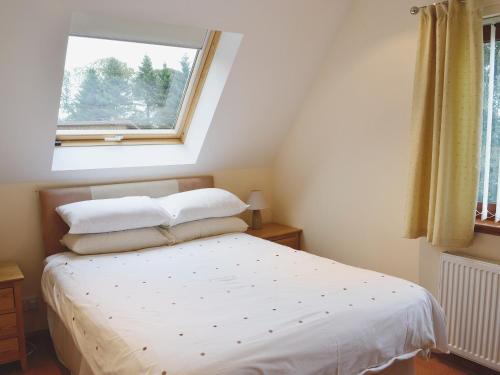 Oakley椴树小屋度假屋的卧室配有白色的床和窗户
