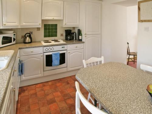 布罗拉Middledrift Cottage的厨房配有白色橱柜和带台面的桌子