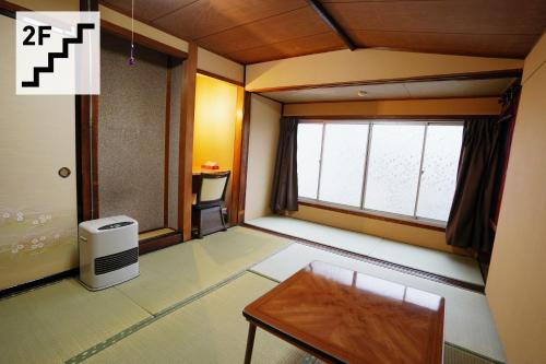 高山Hostel Murasaki Ryokan的小房间设有桌子和窗户