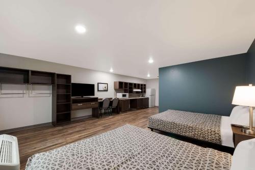 圣安东尼奥WoodSpring Suites San Antonio UTSA - Medical Center的一间卧室配有两张床、一张桌子和一台电视。