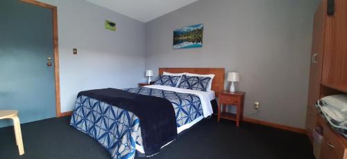 罗托鲁瓦库图海滩住宿加早餐旅馆的一间卧室配有一张带蓝色和白色棉被的床