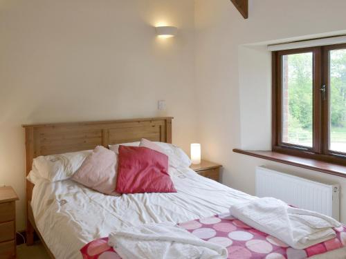 Poundstock霍姆蕾乡村别墅的一张带粉色和白色枕头的床和窗户