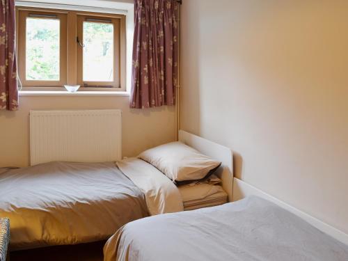 Westbury-sub-MendipThe Threshing Barn的一间卧室设有两张床和窗户。