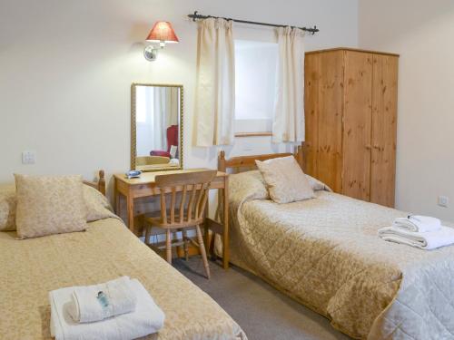 北威灵厄姆老奶牛场乡村别墅的一间卧室配有两张床和一张带镜子的书桌