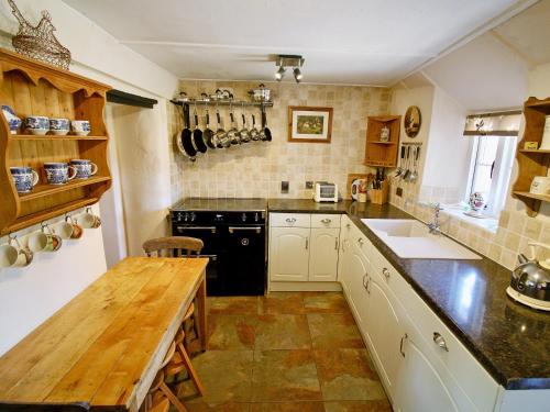 Brompton Ralph奥德维尔乡村别墅的厨房配有木桌和黑色家电