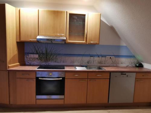 卡珀尔恩Ostseeblick im Andersenhof的厨房配有木制橱柜和炉灶烤箱。