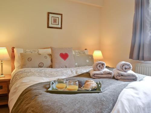 Hoel-galedTy Newydd Cottage的床上的食品托盘,包括毛巾和橙汁
