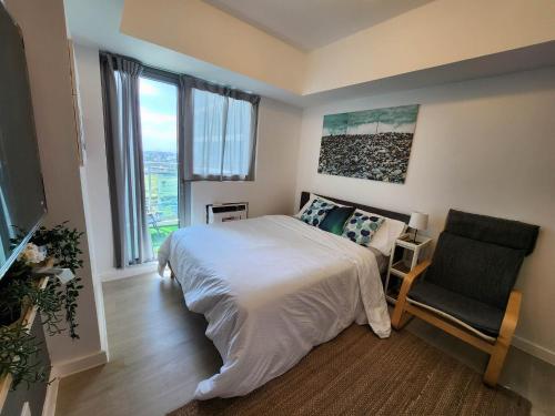 圣费尔南多Amenity View Studio Azure North的一间卧室配有一张床、一把椅子和窗户。