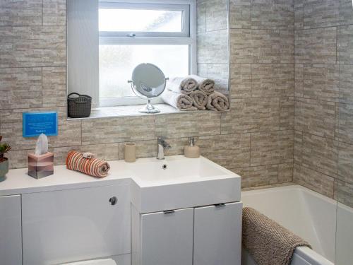 Caeathro依多尔乡村别墅的浴室配有白色水槽和浴缸。