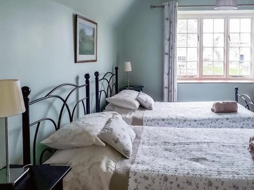 Hovingham豪斯农场乡村别墅的卧室设有两张单人床和窗户。