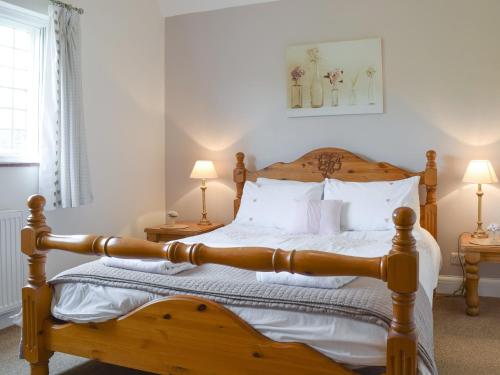 大米森登金斯希尔农场小屋酒店的一间卧室配有带白色枕头的木床