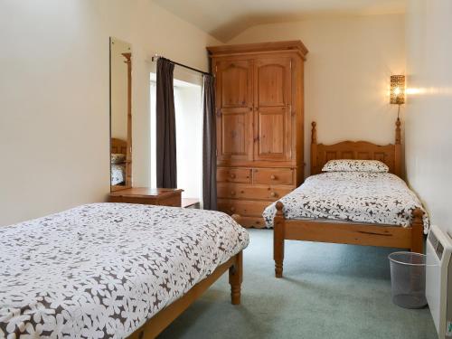 Brynsiencyn玉米阁楼乡村别墅的一间带两张床和梳妆台的卧室