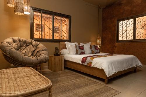 洛美Nomads的一间卧室配有一张床、一把椅子和窗户。