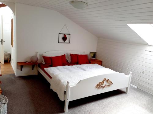雷特温克尔Landhaus Bellecôte的卧室配有带红色枕头的白色床