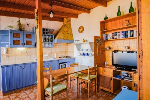 Almáciga卡萨那格公寓的厨房配有蓝色橱柜和一张桌子及一台电视机