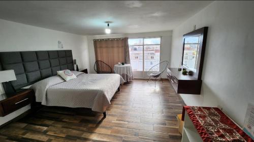 萨卡特卡斯depa #5 recién remodelado en planta alta的一间卧室配有一张床、一张桌子和一个窗户。
