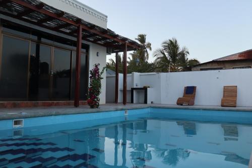江比阿Jambo Jambiani Beach Villa, Beautiful private villa at 2 minutes from the Beach的一座带游泳池和两把椅子的房子