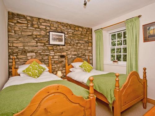 Bellerby樱桃树乡村别墅 的一间卧室设有两张床和石墙