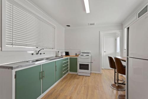 林肯港Shaen Street Motel的厨房配有绿色橱柜和白色家电