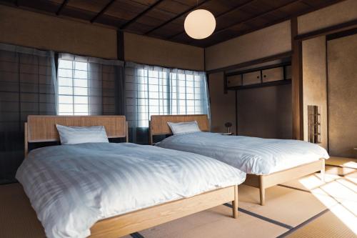Sasayamataos 丹波の風土を感じられる一棟貸切の宿的带窗户的客房内的两张单人床