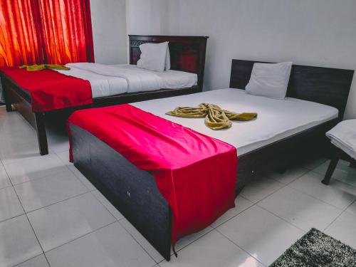 PattipolaThe Green View的配有红色和白色床单的客房内的两张床