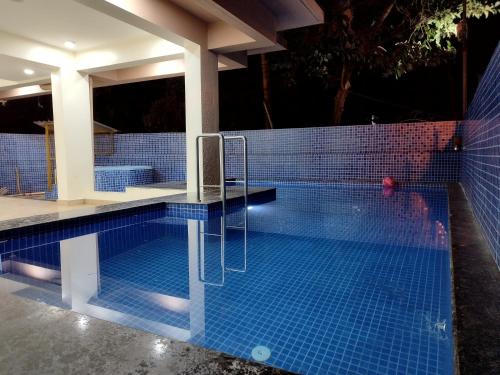 巴加C V Inn的一座位于房子一侧的蓝色瓷砖游泳池