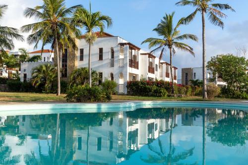 蒙巴萨Sultan Palace Beach Retreat Mombasa的游泳池前棕榈树的房子