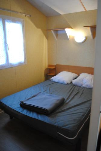 La Boissière-de-MontaiguMobil Home camping 3*** piscine chauffée的一间卧室,床上放着手提箱