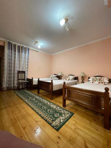 布哈拉Hotel Al Mansur的一间带两张床的卧室和地毯