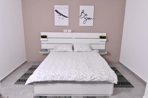 海法Deluxe Basement Apartment Bahai's Garden的卧室配有白色的床和白色床头板