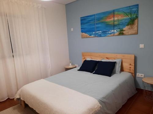 蓬德利马Casa da Dina的卧室配有一张床,墙上挂有绘画作品