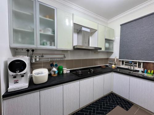 芙蓉3R D'Latania Senawang的厨房配有白色橱柜和黑色台面