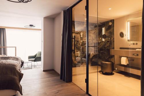 索尔登斯科恩奥西赫特酒店的卧室设有玻璃淋浴间和水槽