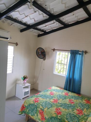 里奥圣胡安Margarita的一间设有床铺的卧室,位于带蓝色窗帘的房间