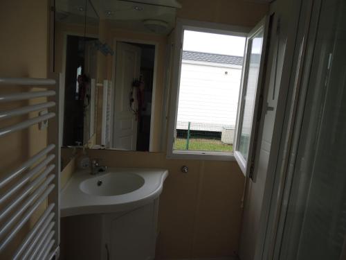 塔勒蒙Le Vert Océan的一间带水槽和镜子的浴室以及窗户。