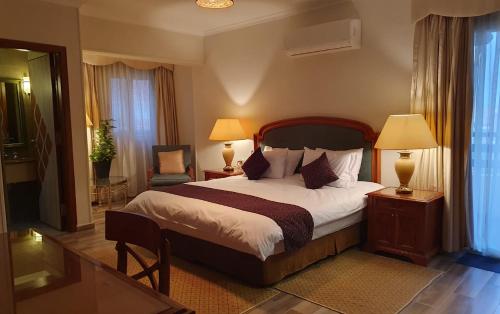 开罗Kemet Boutique Hotel的一间卧室配有一张大床、两盏灯和一把椅子