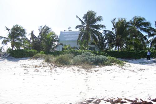 总督港Mon Soleil home的棕榈树海滩上的白色房子