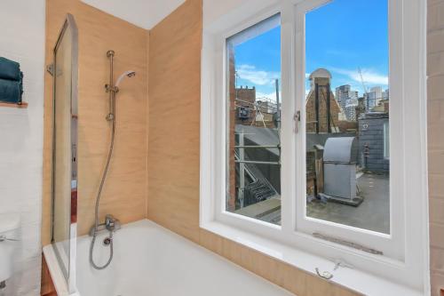 伦敦Stunning Shoreditch Loft Warehouse Style Apartment的带浴缸的浴室和窗户。