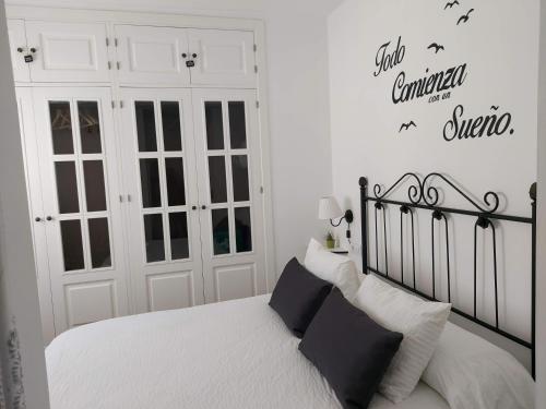 加的斯ÁTICO VICTORIA BEACH的卧室设有黑白色的床和白色的墙壁。
