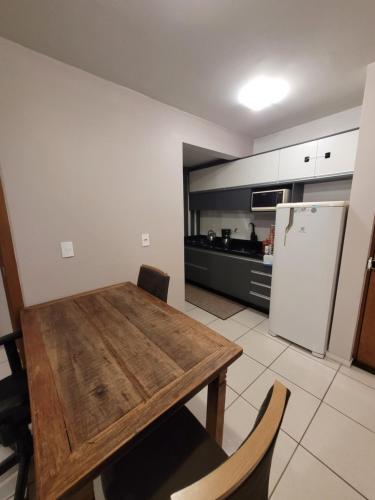 沙佩科Apartamento centro Efapi ideal para trabalho ou estudo的厨房配有木桌和冰箱。