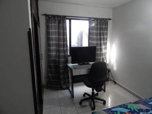 布卡拉曼加Excelente ubicación的一间卧室配有一张桌子、一台电脑和一个窗口