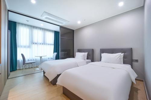 全州市Jeonju Signature Hotel&Residence的酒店客房设有两张床和一张桌子。