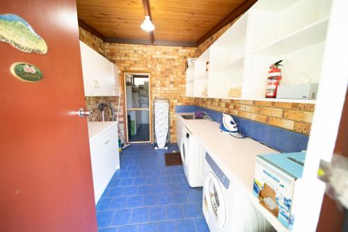 贝瑟尼Blickinstal Holiday Retreat的厨房配有白色橱柜和蓝色瓷砖地板。