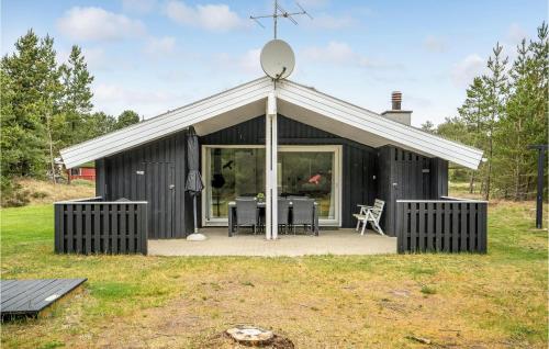 博利尔马克Cozy Home In Rømø With Kitchen的黑色的棚屋,有白色的屋顶和桌子