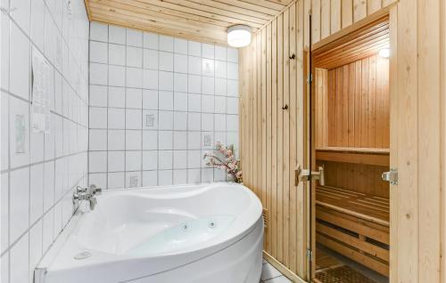 克里斯蒂安斯费尔德Pet Friendly Home In Christiansfeld With Sauna的浴室设有白色浴缸,拥有木墙